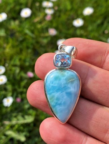 Ein silberner Anhänger mit einem hellblauen Stein und einem kleinen, blauen Zirkon.